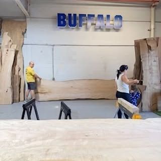 A man and a woman are standing in a room with the word buffalo on the wall.