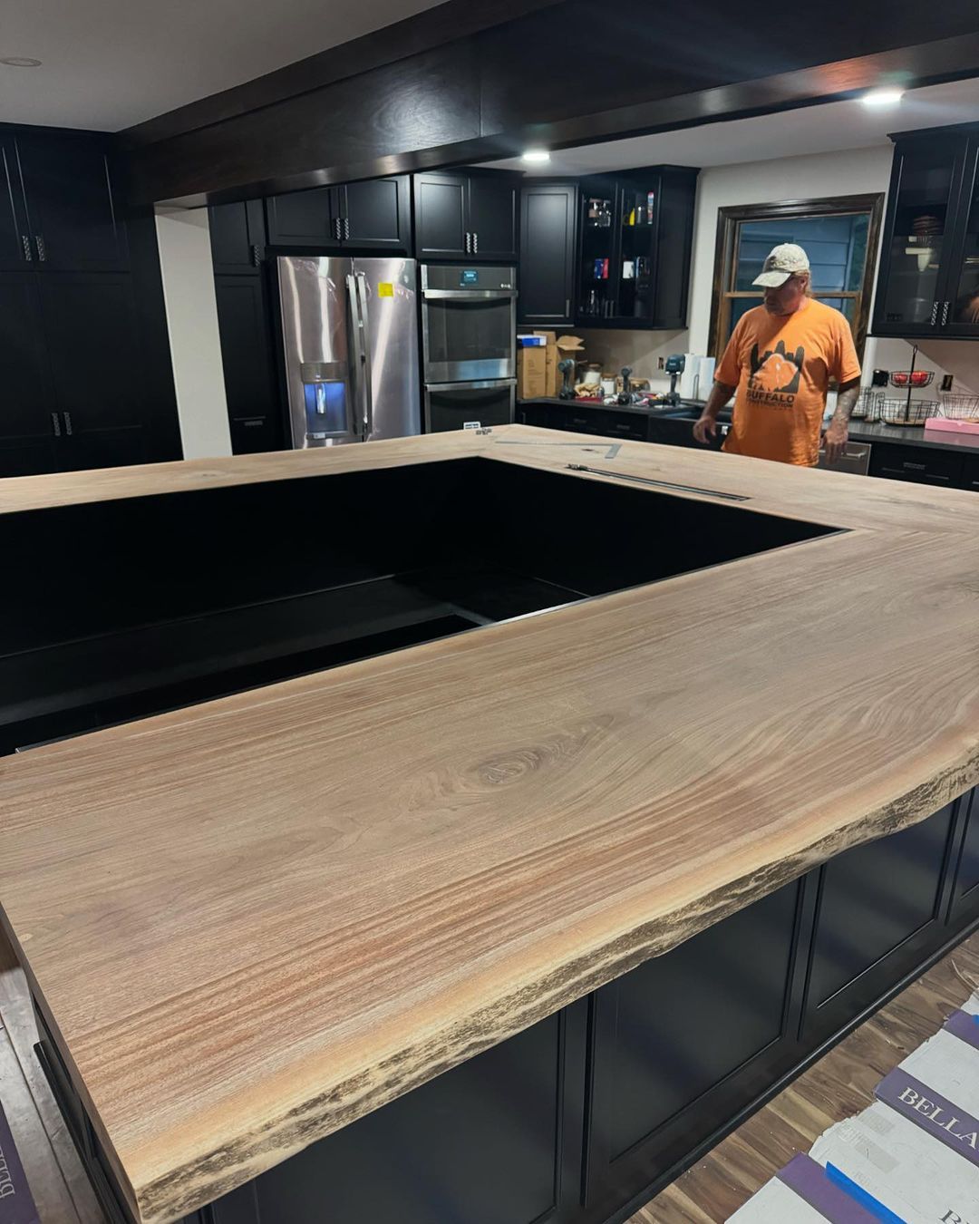 A man standing in a kitchen with a large wooden counter top