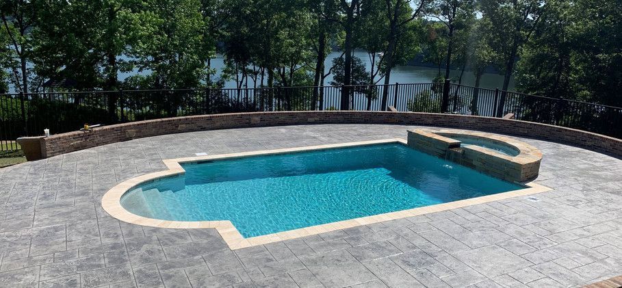 A Large Swimming Pool Is Sitting on Top of A Concrete Patio Next to A Lake - Tuscaloosa, AL - Jeffco Concrete Contractors