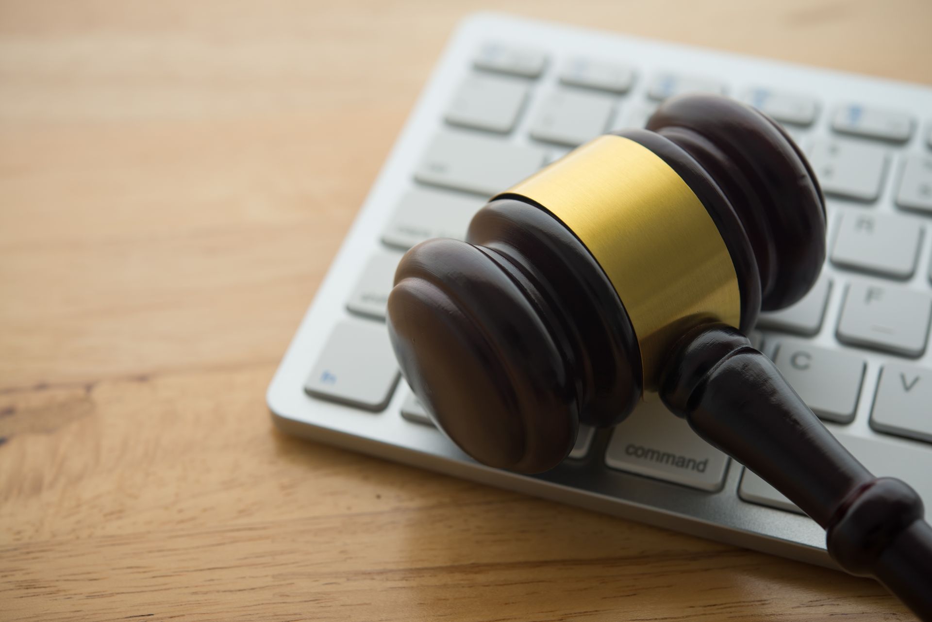 Wooden gavel rests on a white computer keyboard, symbolizing law and technology.