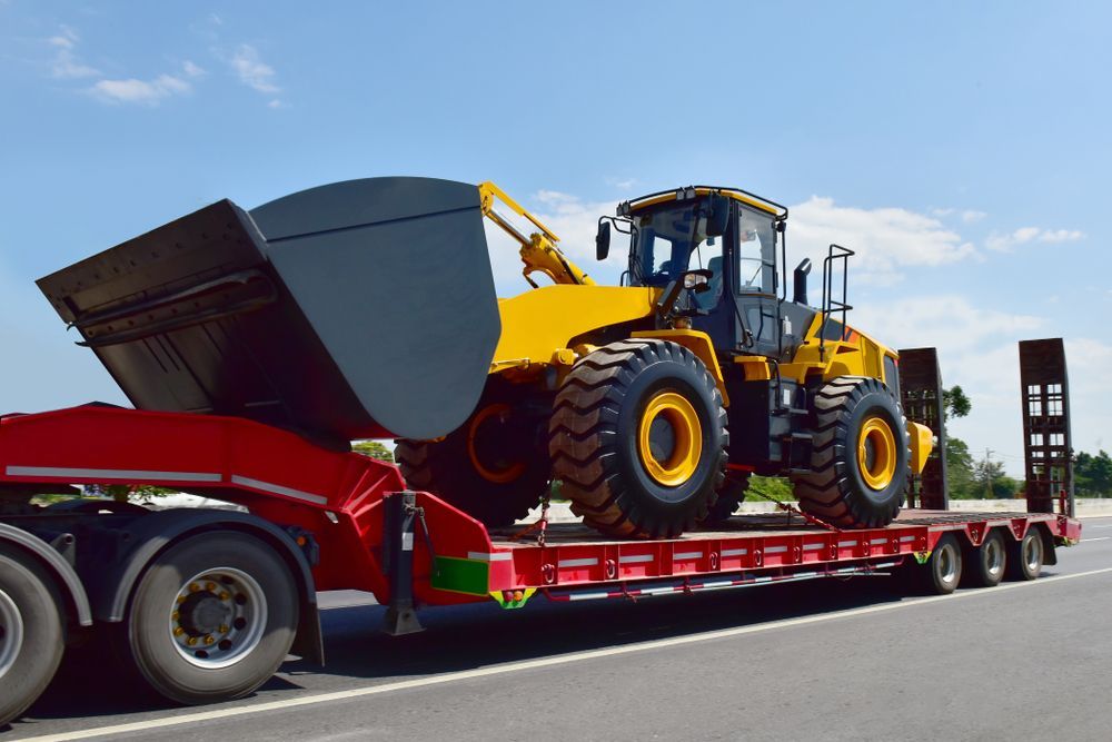 Yellow Loader on a Red Flatbed Trailer — Damon's Earthworks in Chatsworth, QLD