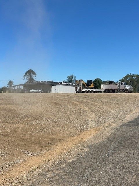 Person Applying Black Sealant to a Dark Asphalt Driveway — Damon's Earthworks in Chatsworth, QLD
