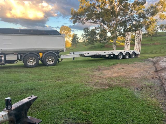 Yellow Excavator on a Flatbed Trailer Being Hauled — Damon's Earthworks in Chatsworth, QLD