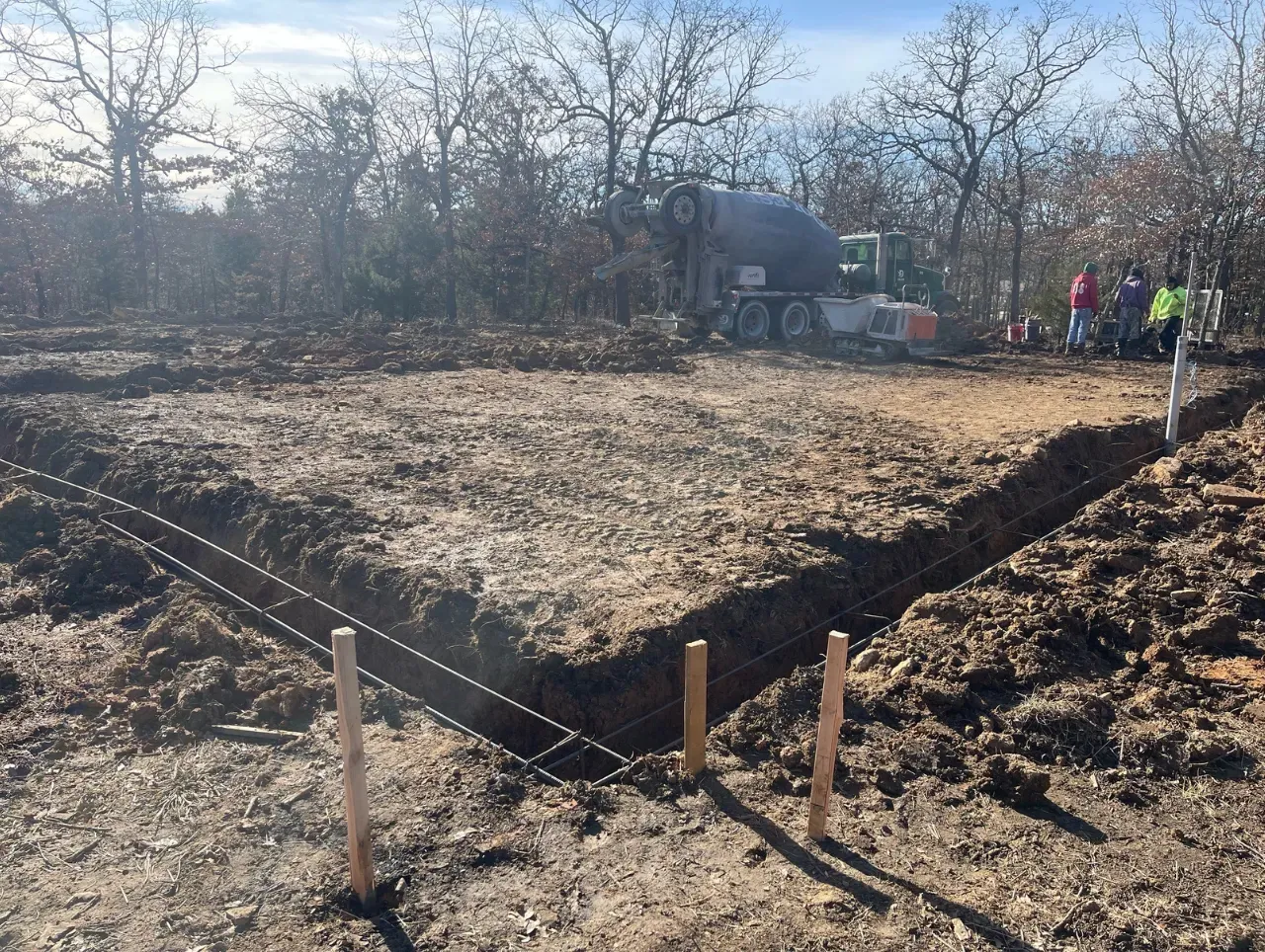 Construction site with a cement truck pouring concrete into a prepared foundation.