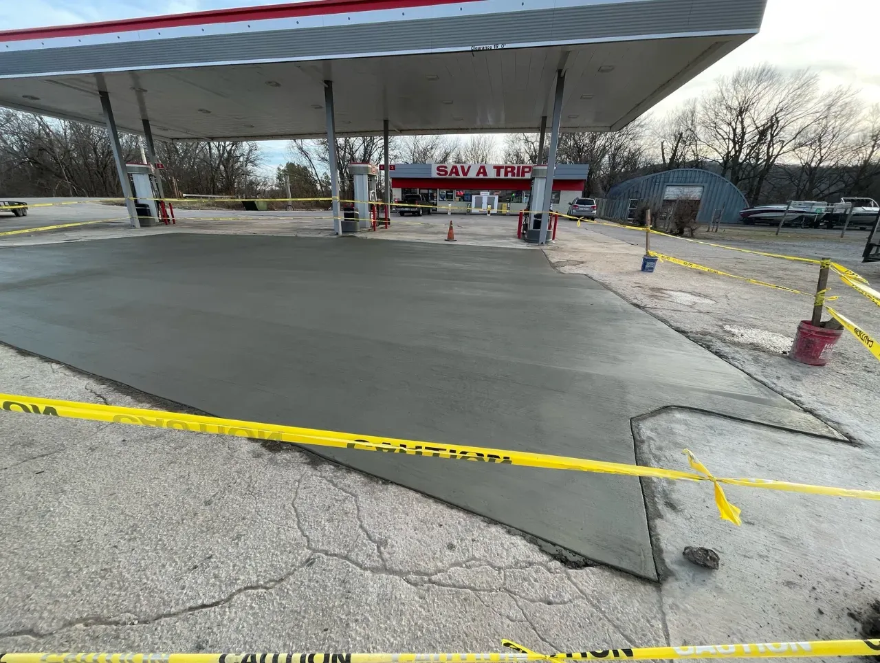 Gas station with freshly poured concrete, roped off with caution tape.
