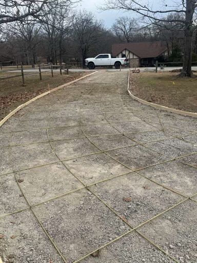 Driveway construction with gravel base and wire mesh reinforcement. White pickup truck parked in background.