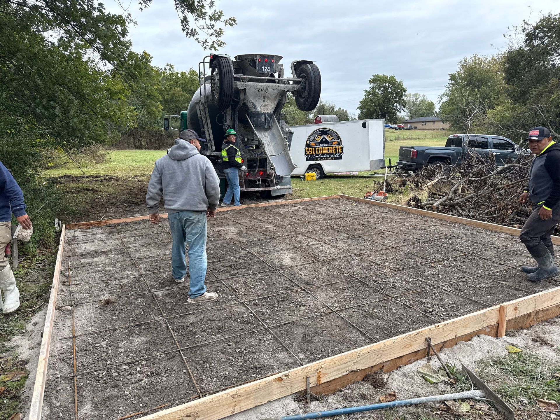 Concrete being poured into a wooden frame at a construction site. Workers are present.