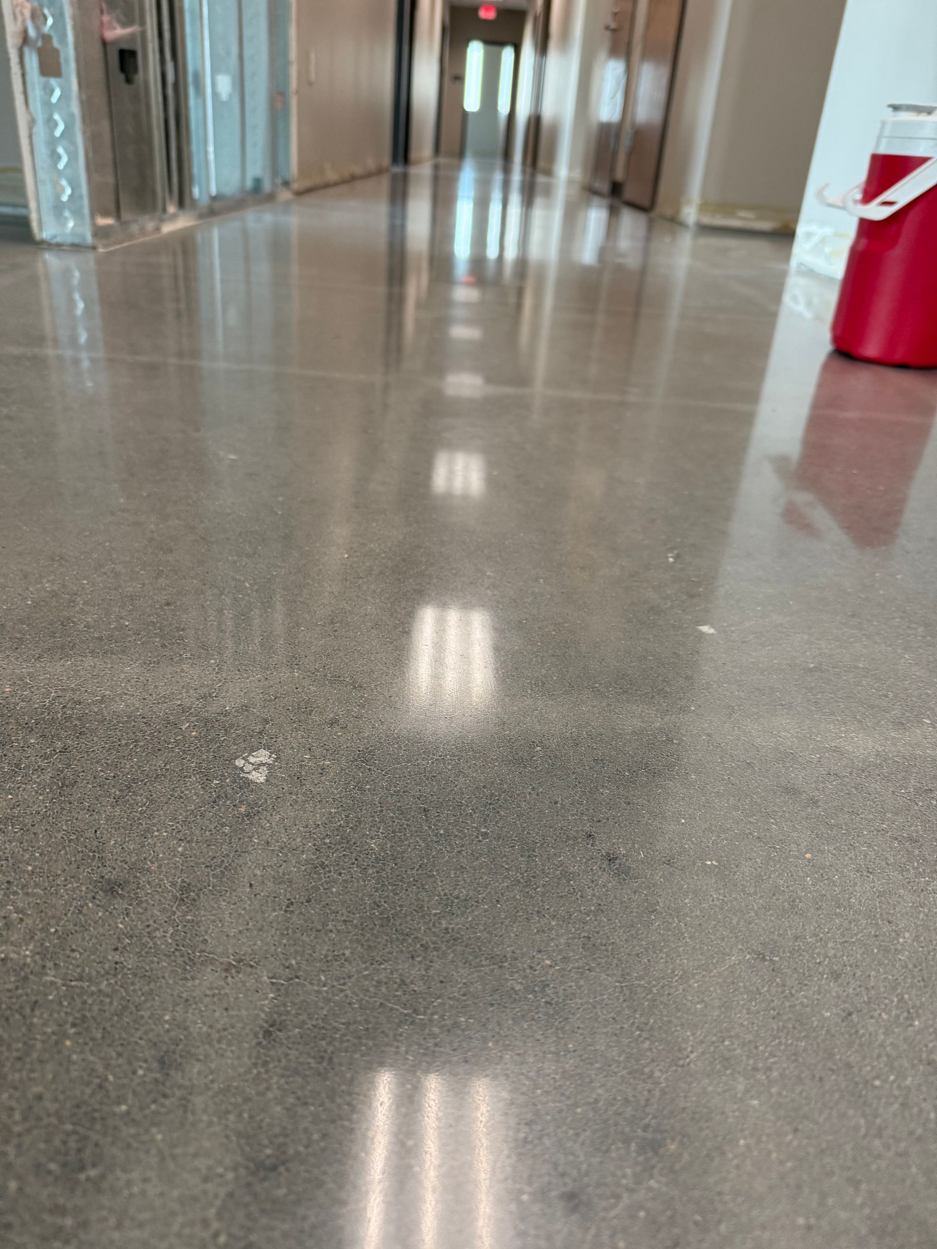 Polished concrete floor reflecting overhead lights in a long hallway.