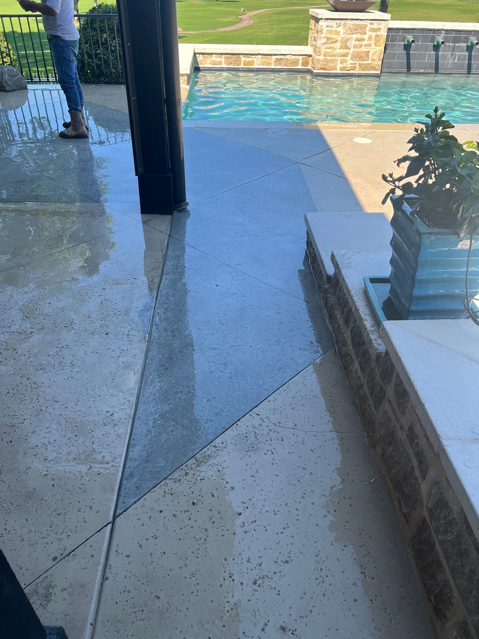 Wet, polished concrete patio with geometric design, next to a pool.