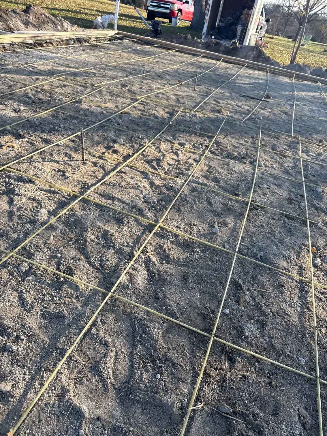 Grid of wire mesh laid on dirt, prepared for concrete pouring outdoors.