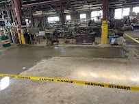 Yellow caution tape surrounds concrete repair in a factory.