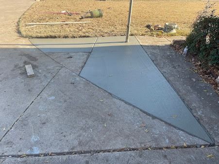 Freshly poured concrete section on a driveway, contrasting with older gray concrete.