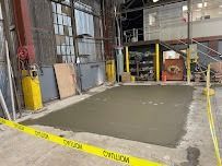 Freshly poured concrete area in an industrial setting, marked by caution tape and equipment.