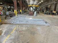 Industrial floor with debris from construction, yellow line, and metal equipment.