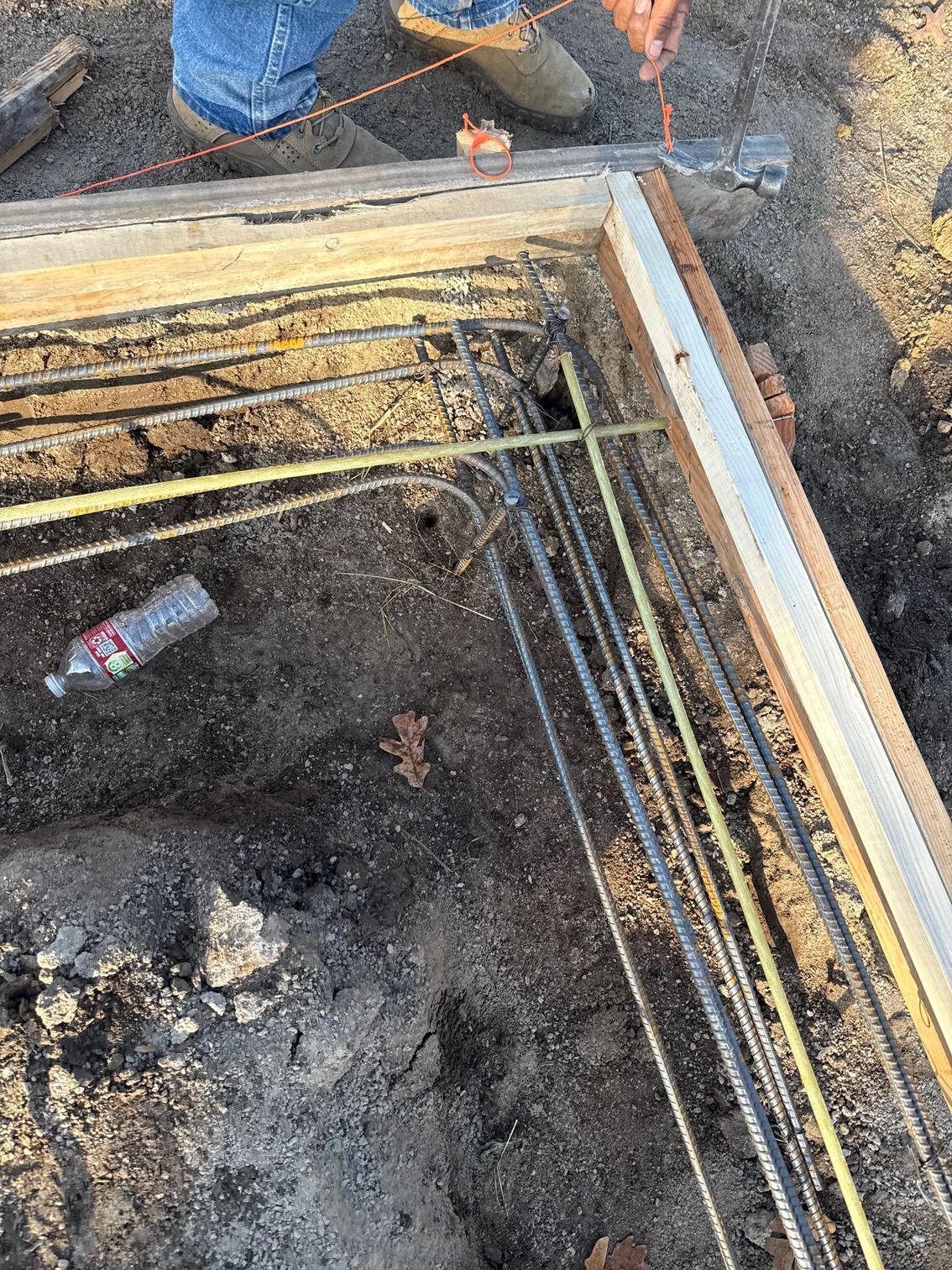 Concrete pathway between a brick building and wooden fence. Sunlight on the horizon.