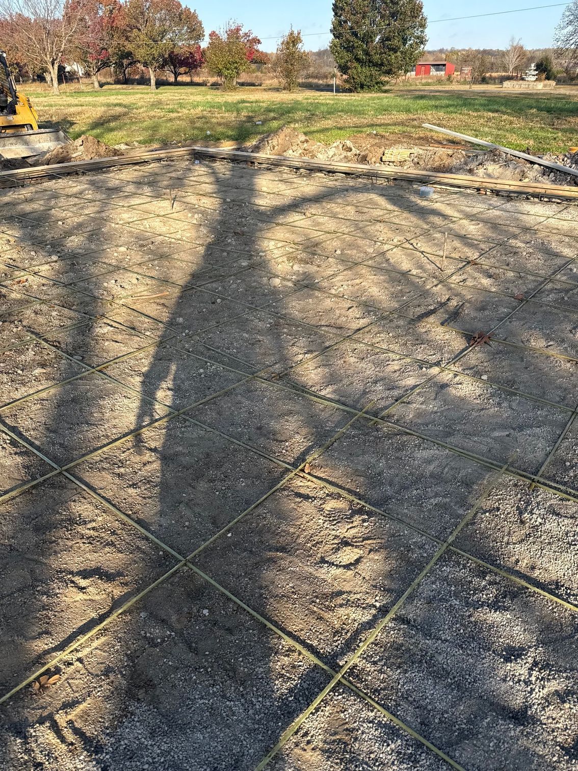 Shadow of a person on gravel ground with metal grid, ready for construction.