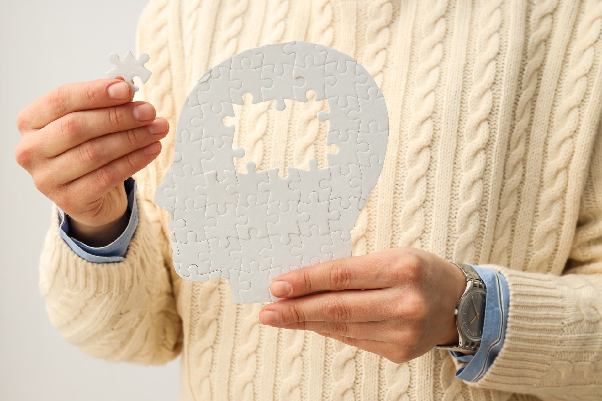 Ein Mann hält ein Puzzle in der Form eines menschlichen Kopfes. Schädel Hirn Verletzung Ergotherapie
