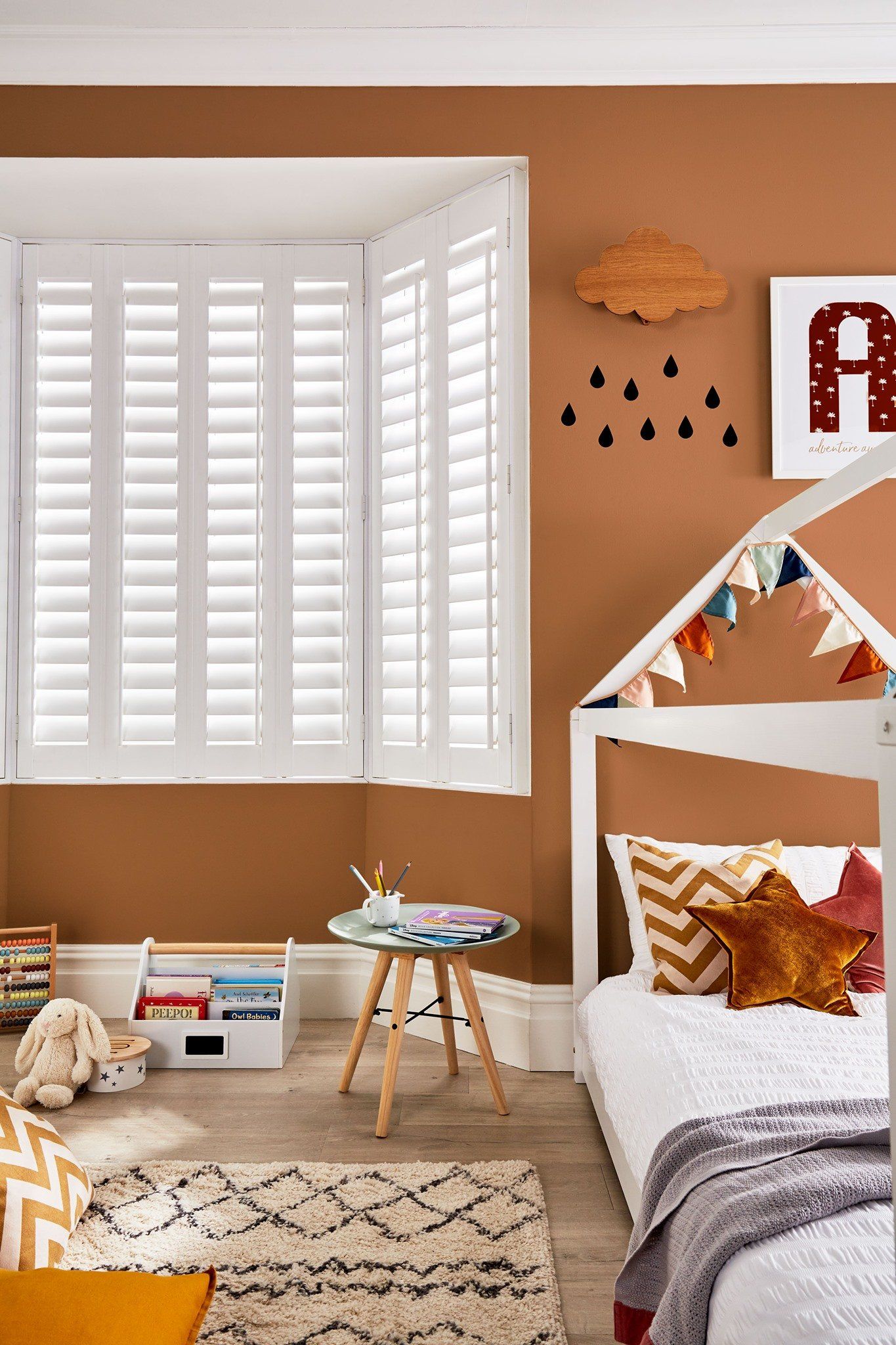 A child 's bedroom with brown walls and white shutters.