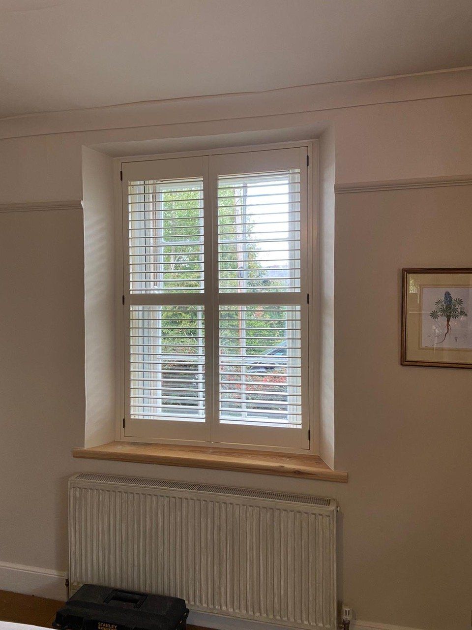 A bedroom with a window with shutters on it and a radiator.