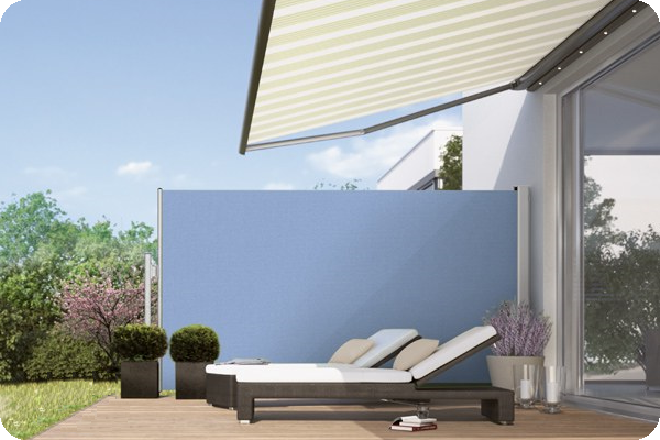 A patio with a striped awning and a blue wall