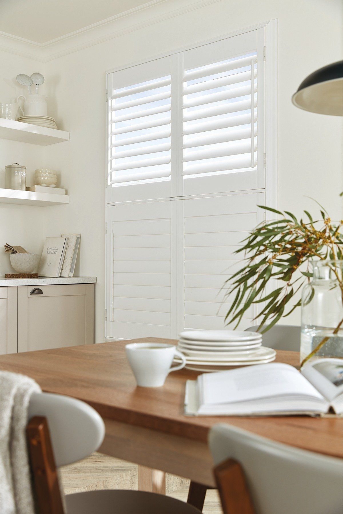 A dining room table with plates , cups , and a book on it.