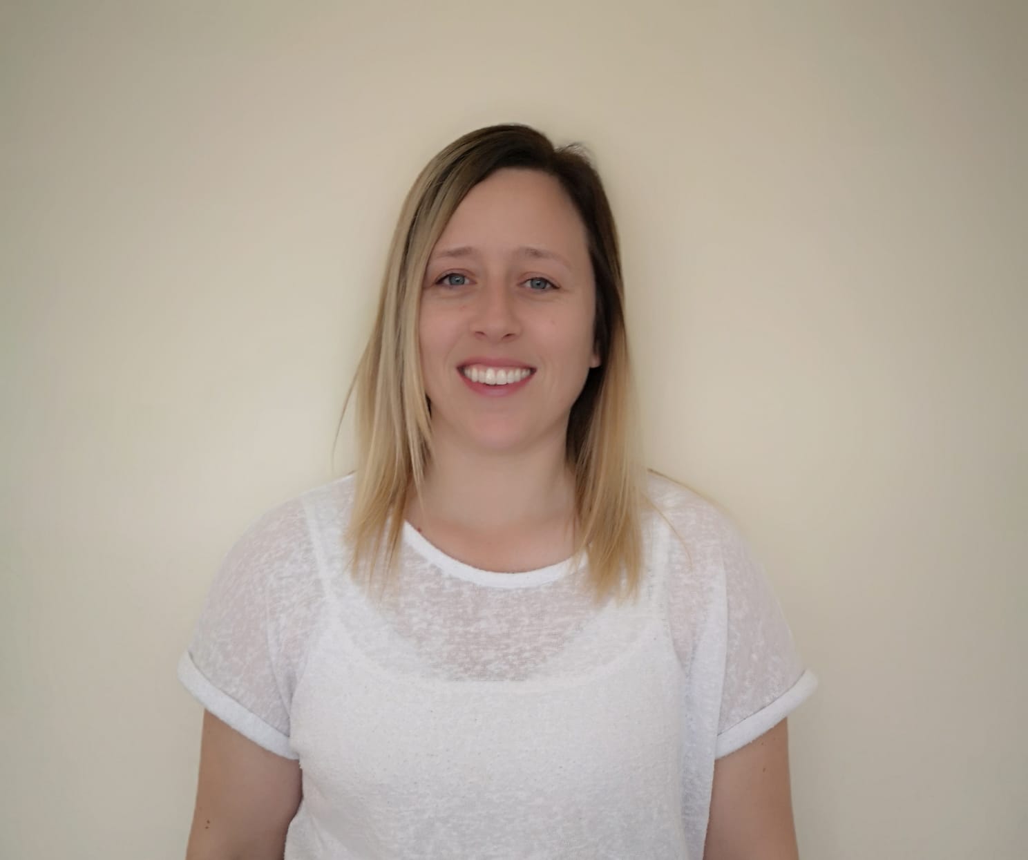 A woman in a white shirt is smiling for the camera.