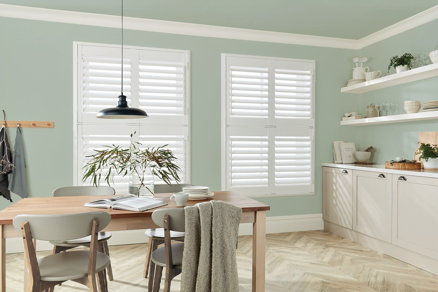 A dining room with a table and chairs and shutters on the windows.