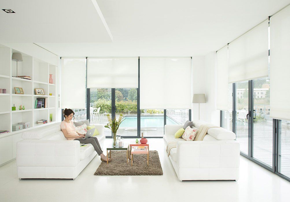 A woman is sitting on a couch in a living room with a laptop.