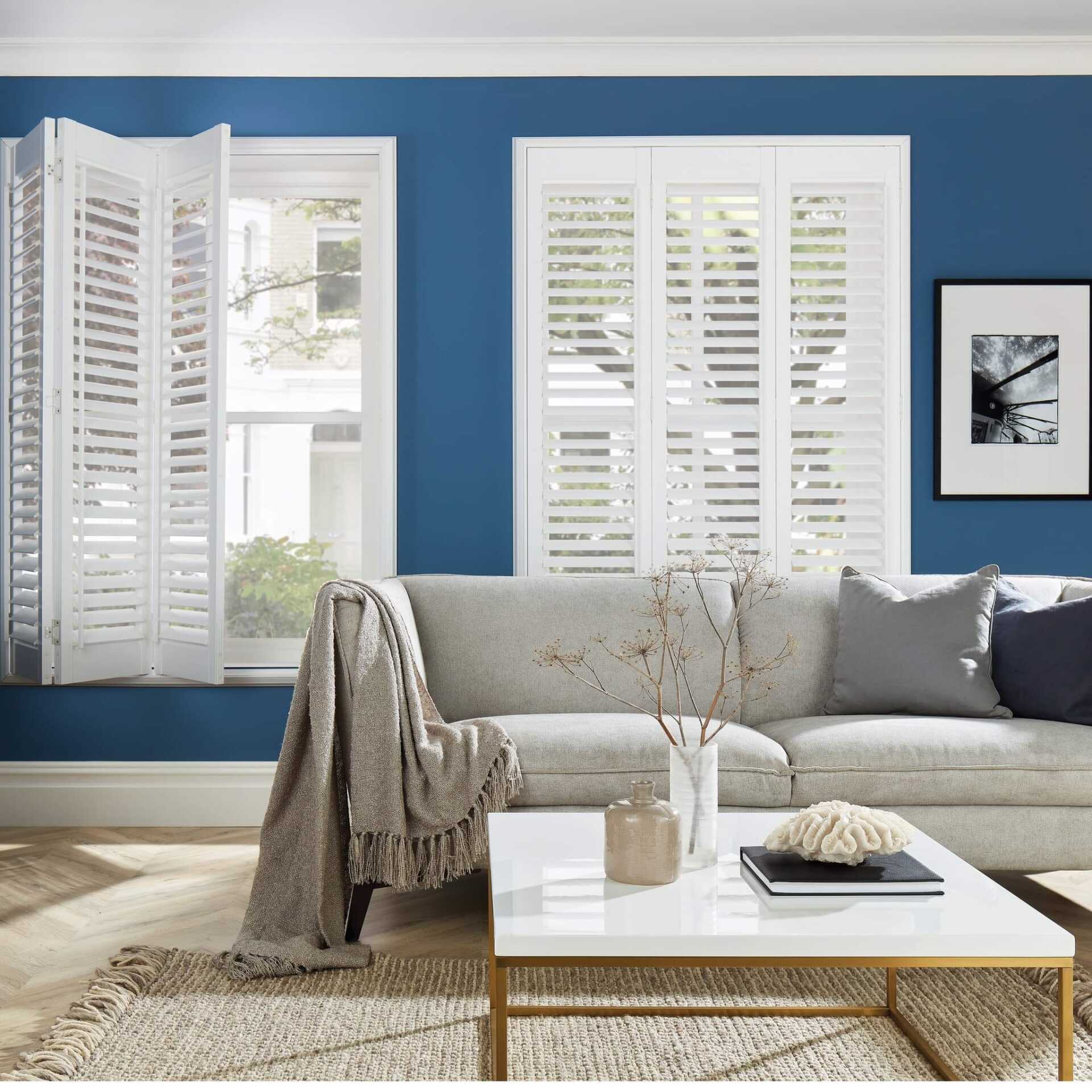 A living room with blue walls and white shutters