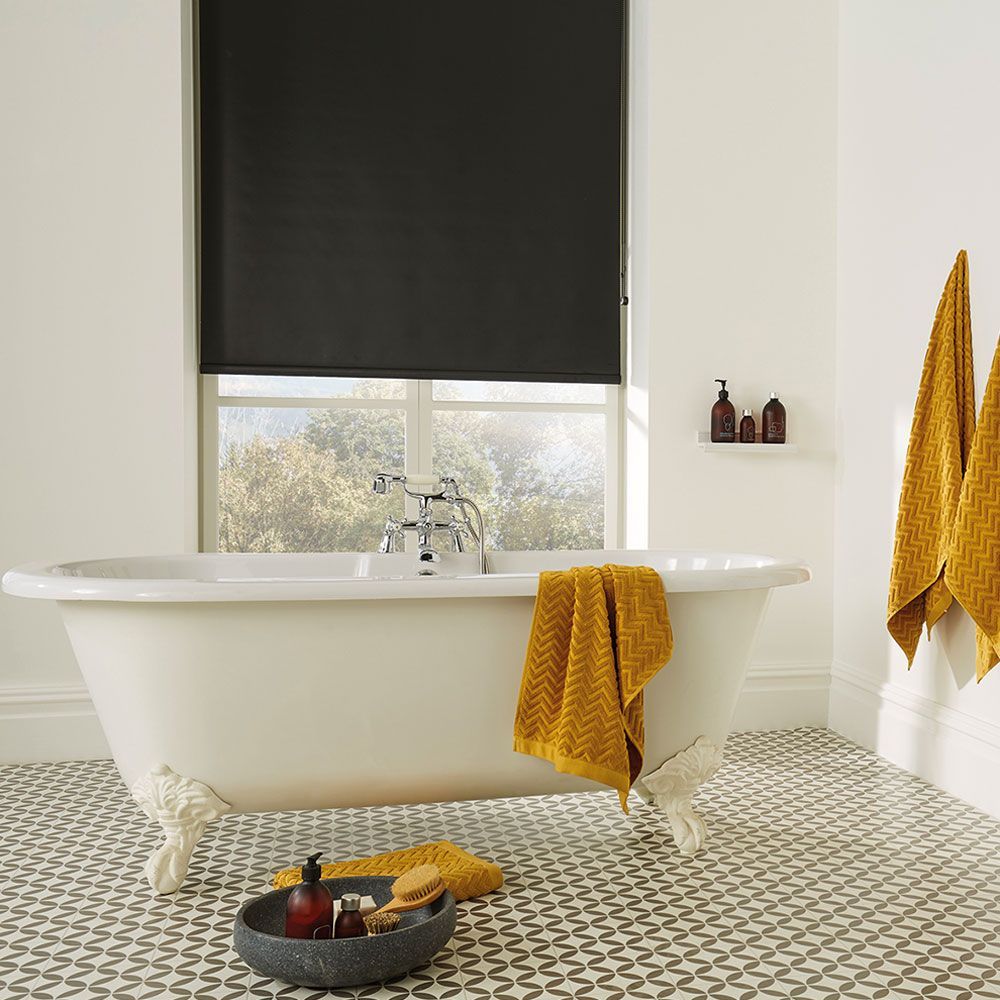 A bathroom with a bathtub and a window with a black blind.