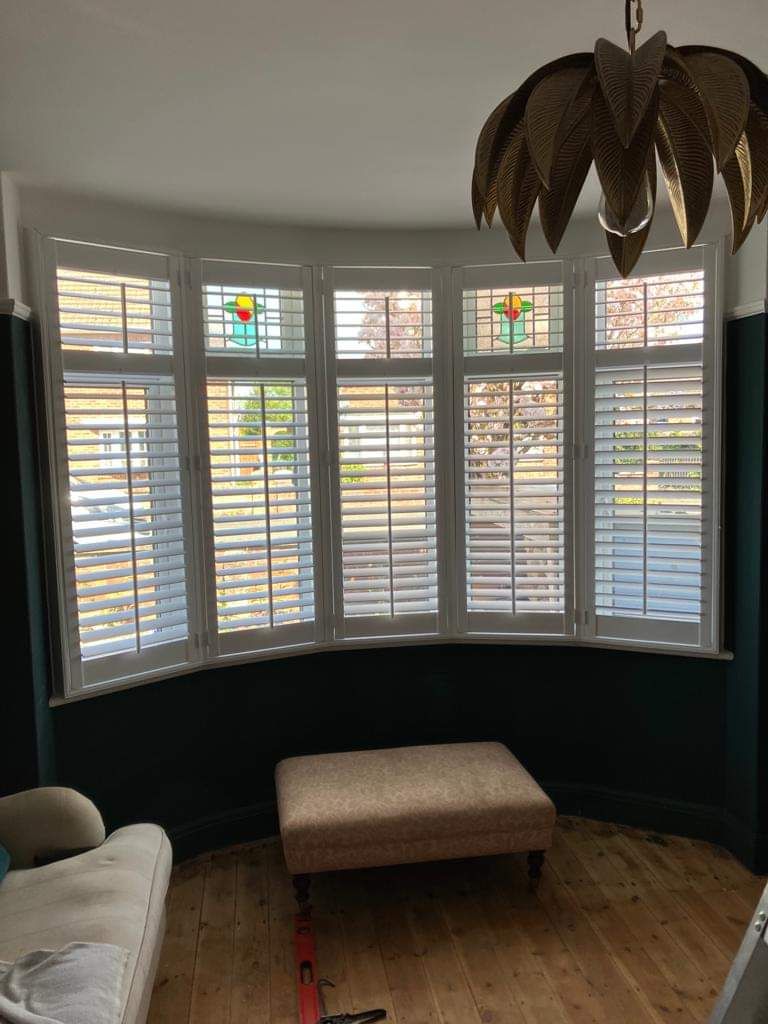 A living room with a couch , ottoman , and stained glass windows.