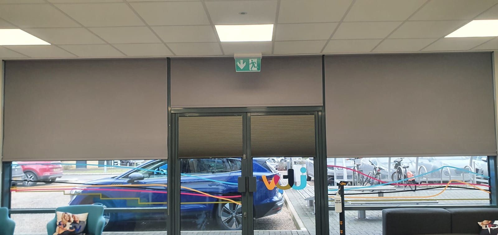 A room with a lot of windows and a green exit sign on the ceiling.