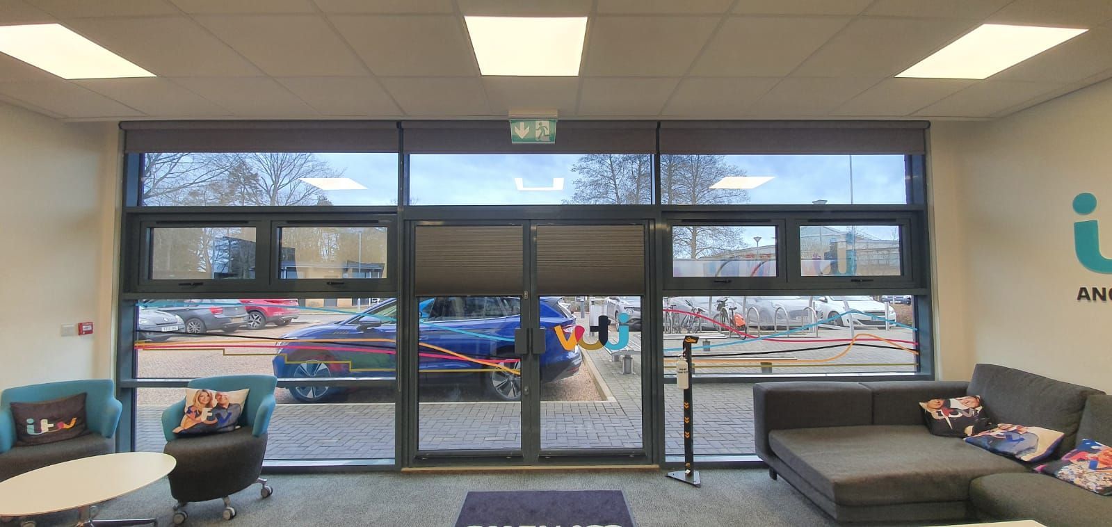 A living room with a couch , chairs , tables and a large window.