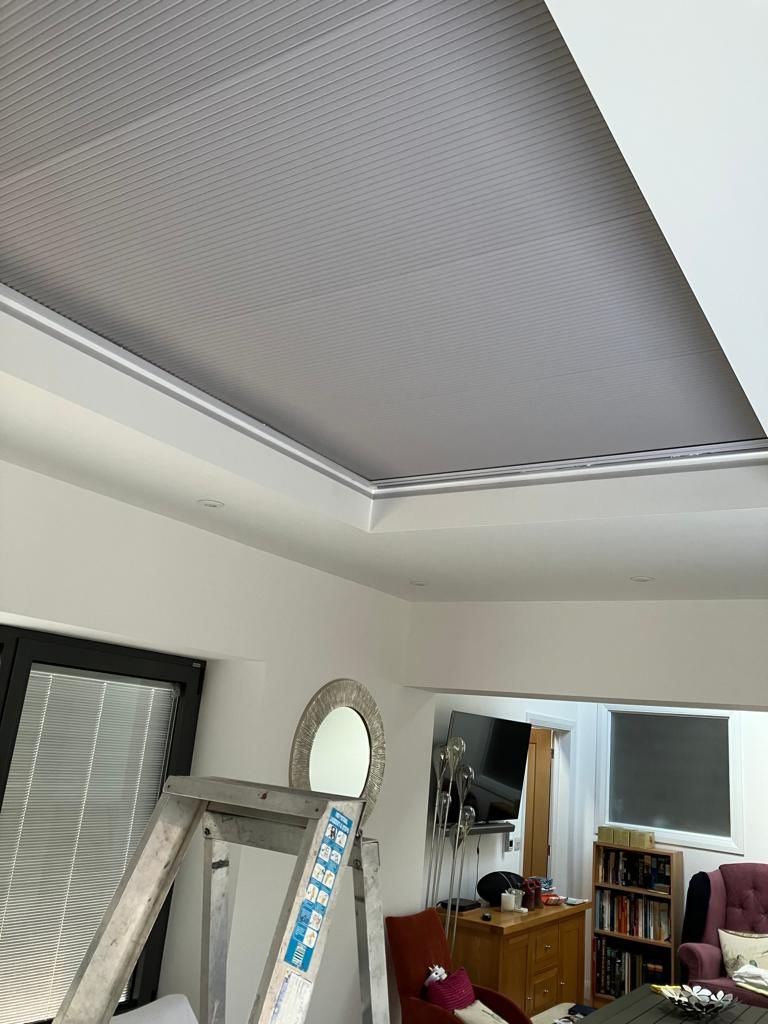 A living room with a ladder and a mirror on the ceiling.