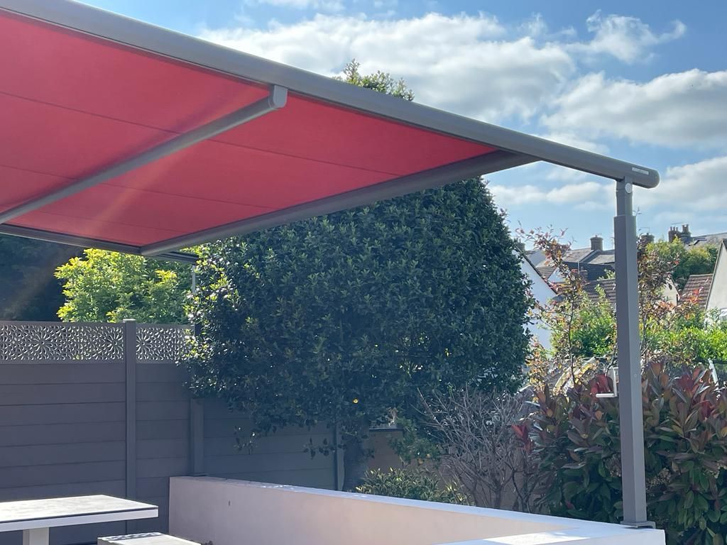 A red awning is covering a patio with tables and chairs.