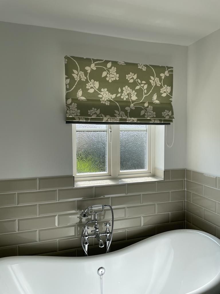 A bathroom with a bathtub and a window with a blind on it.