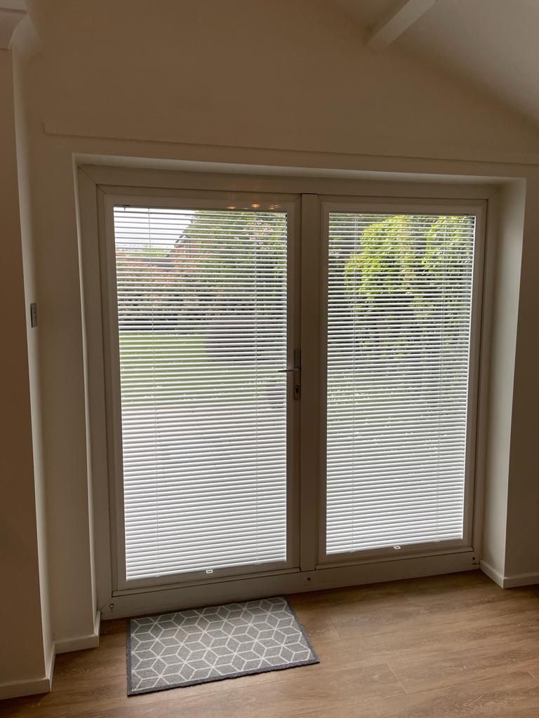A room with a sliding glass door and blinds on it.