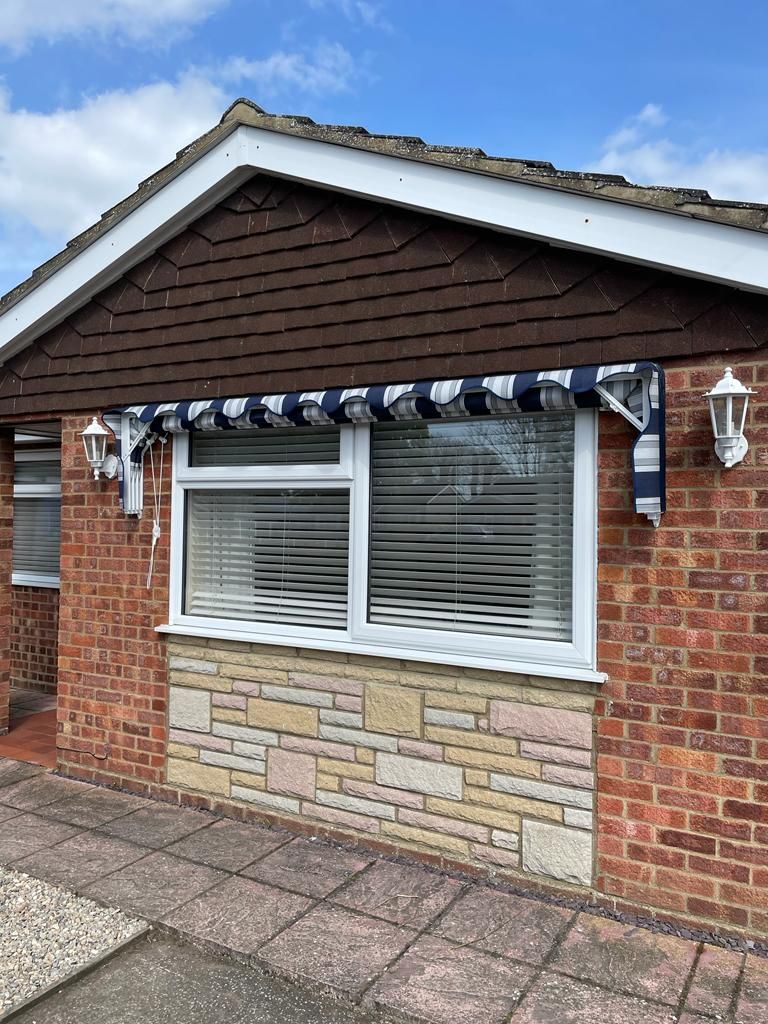 A brick house with a blue and white awning over the window.