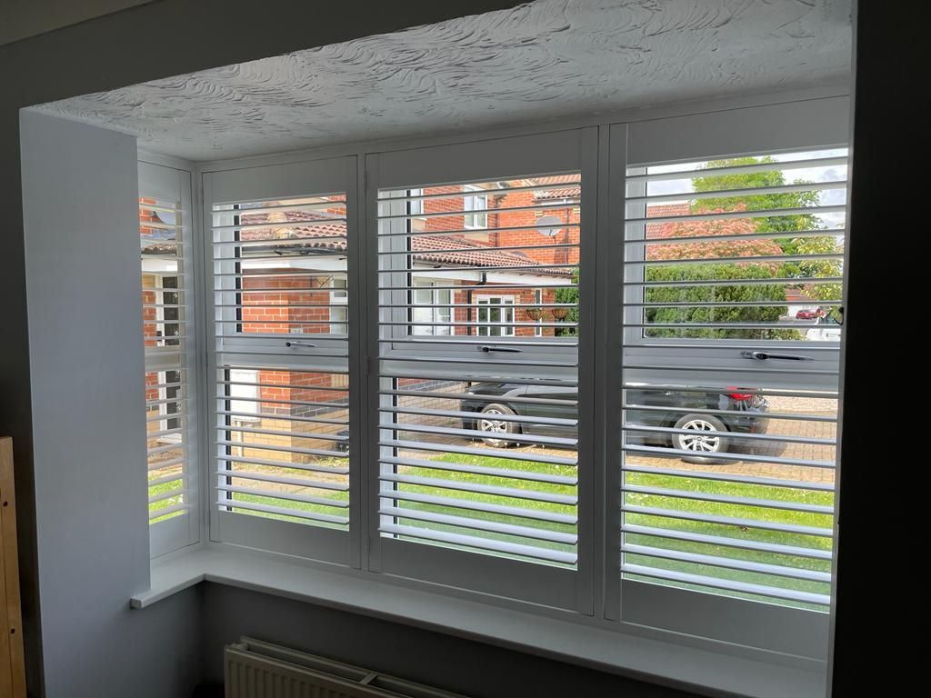 A window with shutters on it and a car in the background.