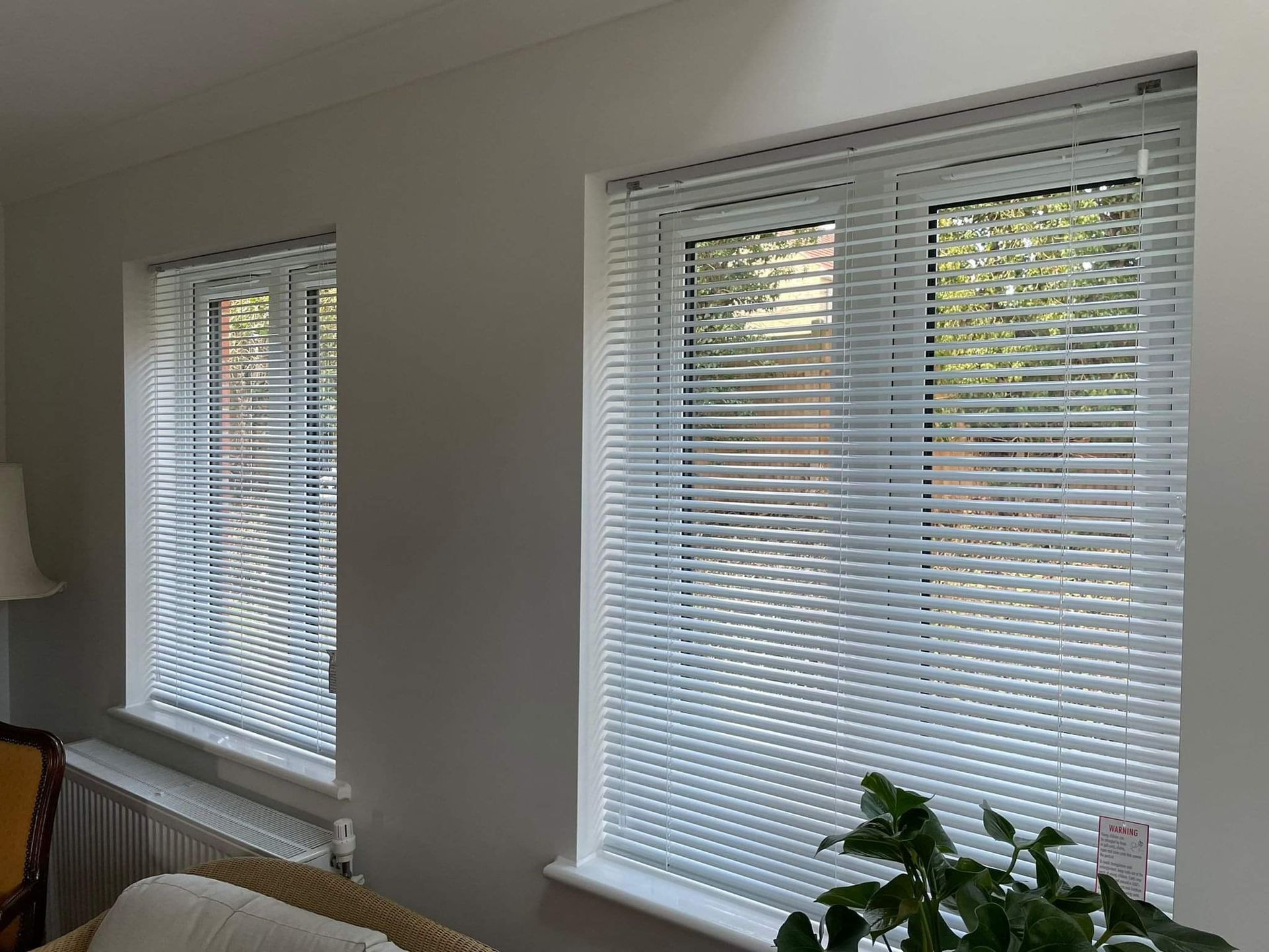 A living room with two windows and white blinds on them.