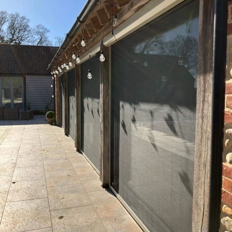 A row of sliding screen doors on a brick building