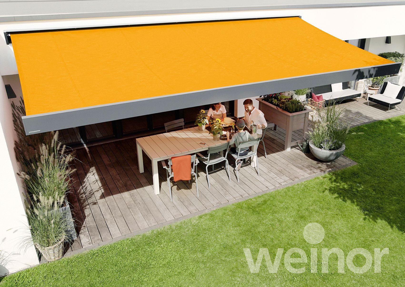 A couple sits under an orange awning on a patio