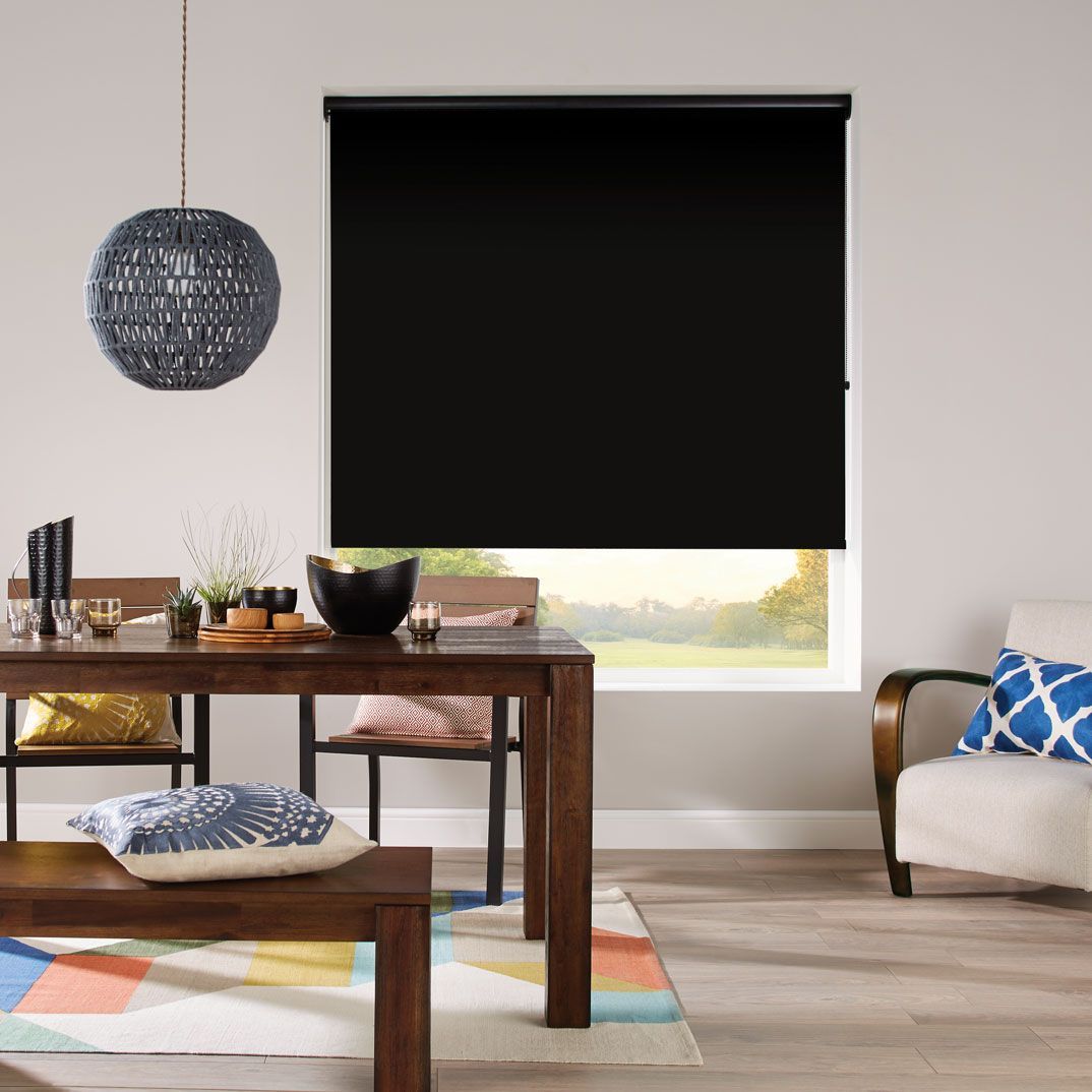 A living room with a table and chairs and a black blind on the window