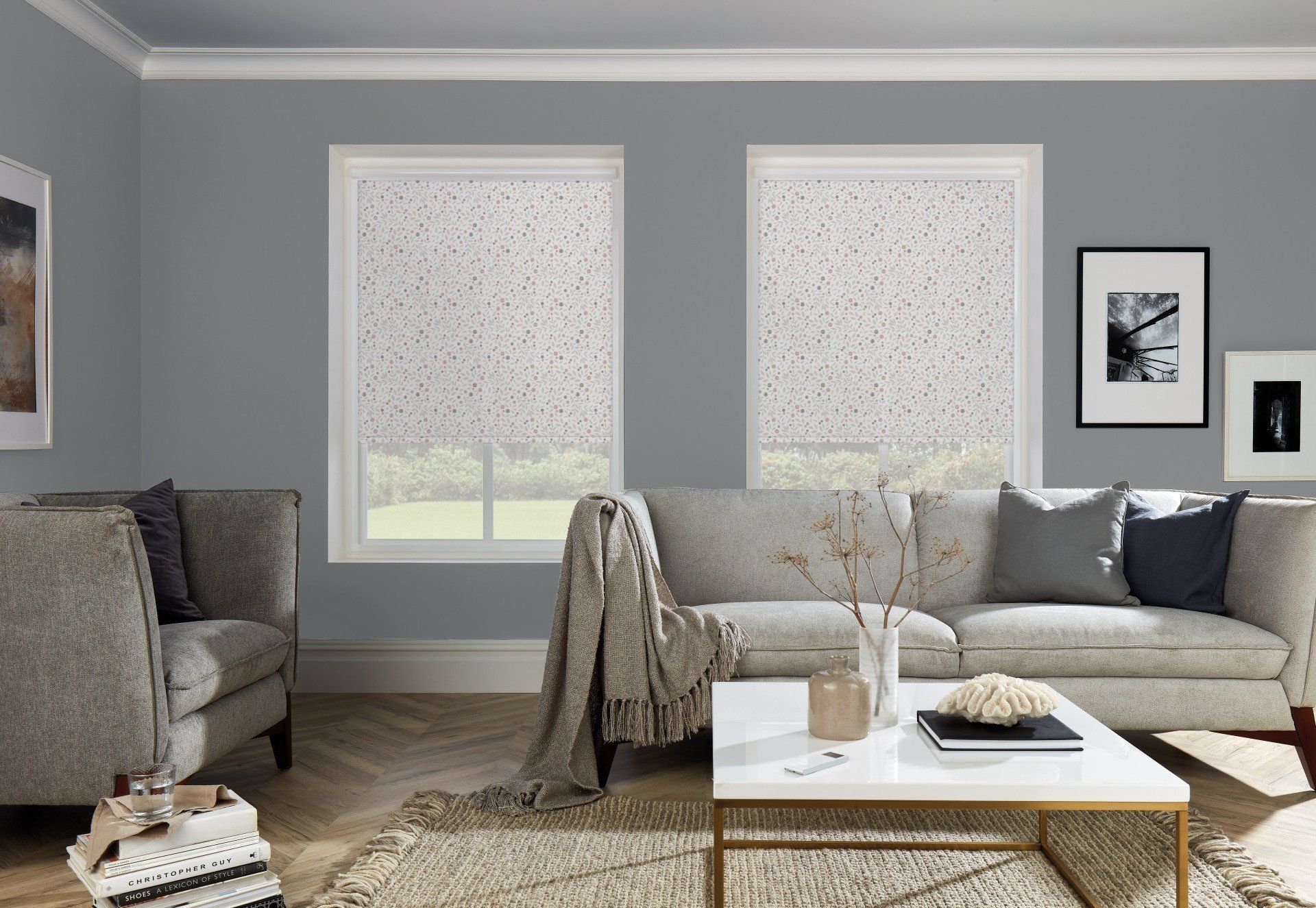 A living room with a couch , chair , coffee table and two windows.