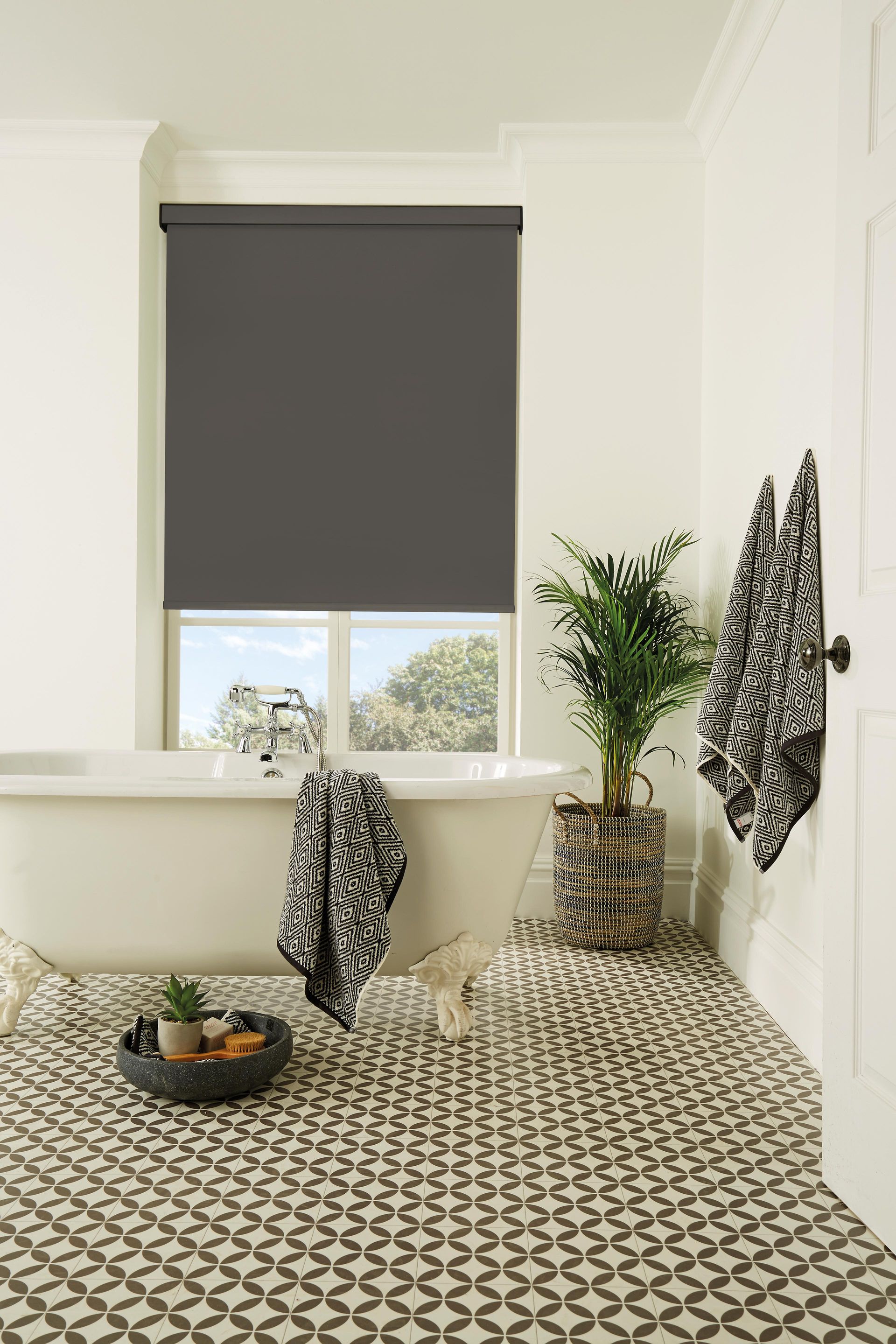 A bathroom with a bathtub and a window with a black blind.