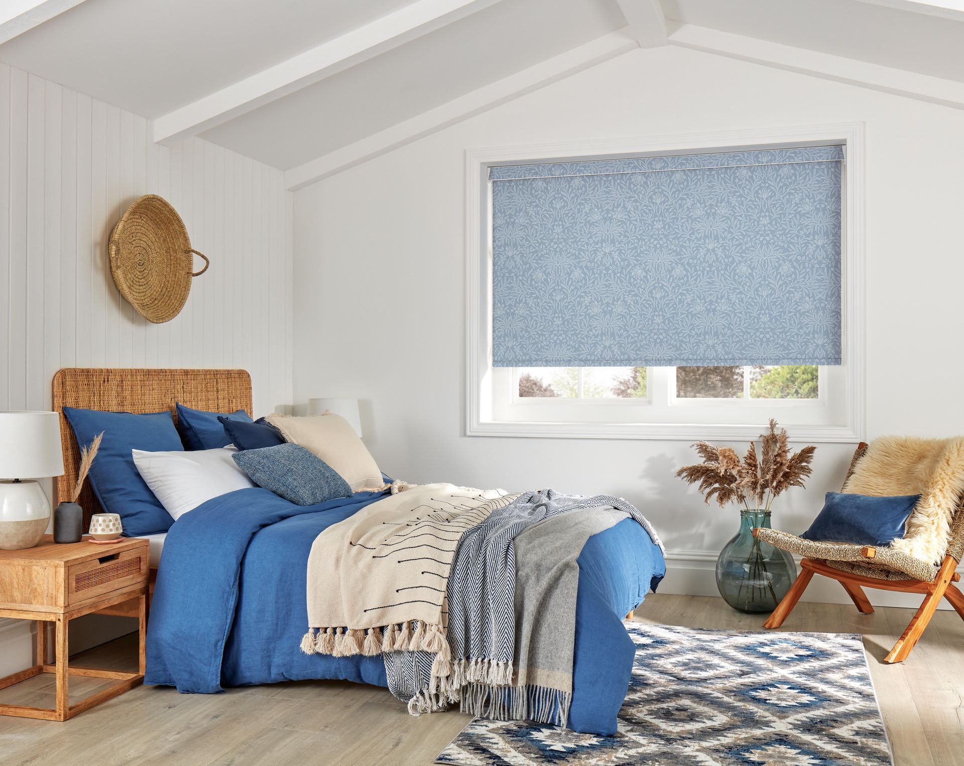 A bedroom with a bed , chair , nightstand and rug.