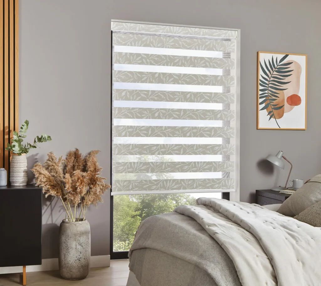 A bedroom with a bed and a window with a blind on it.