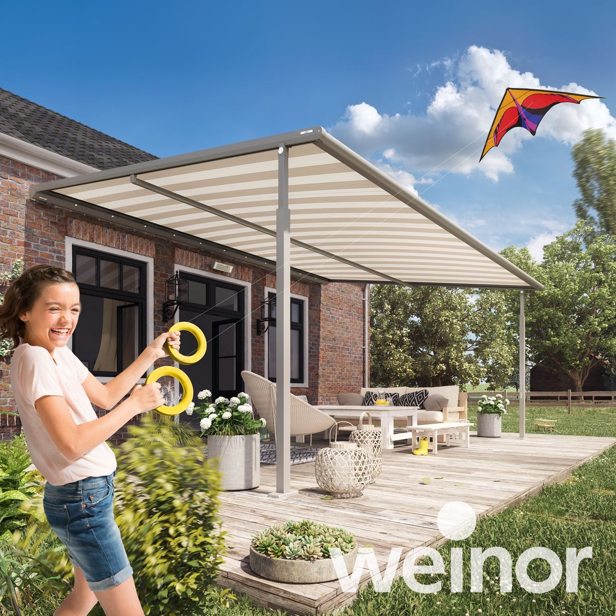 A little girl is playing with a kite on a patio.