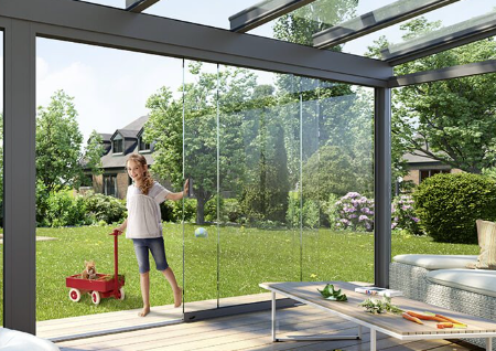 A woman is standing on a patio under a glass roof.