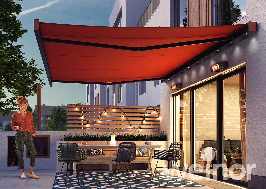 A woman is standing under a red awning on a patio.